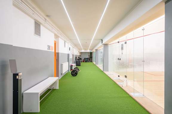 A long hallway with a green carpet and a bench on the side.