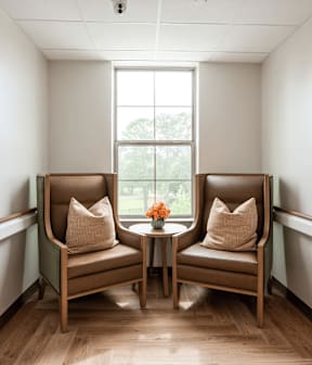 Two chairs are placed in a room with a window.