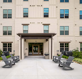 A building with a covered walkway and benches in front.
