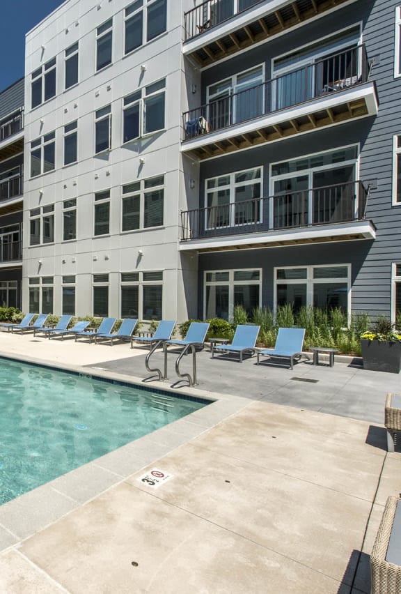 an apartment building with a swimming pool and lounge chairs
