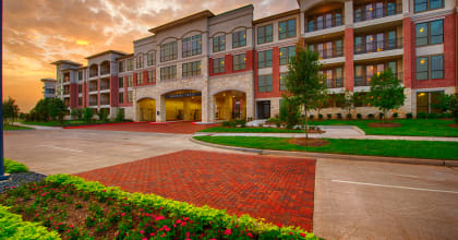 an exterior view of an apartment building at sunset at Imperial Lofts, Sugar Land, TX