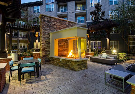 a courtyard with a fireplace and tables and chairs