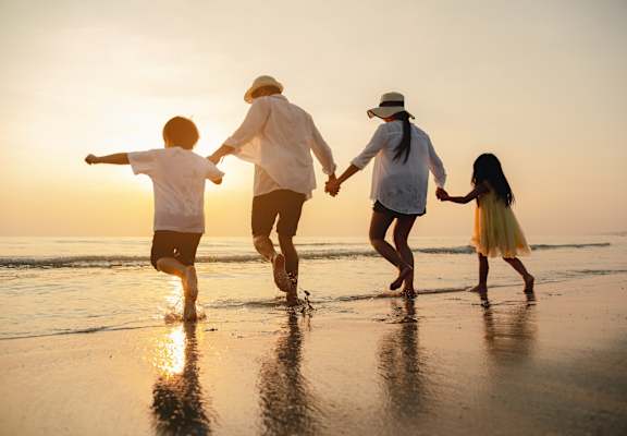 Family Holding Hands and Walking Along the Beach During Sunset