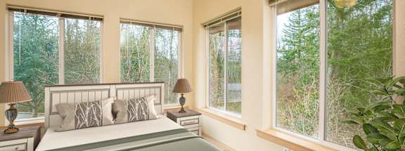 A bedroom with a bed, two lamps, and a ceiling fan. at Fairview Village Apartments, Fairview, OR, 97024