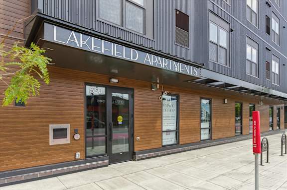 The front of the Lakefield Apartments building with a red post box on the sidewalk.