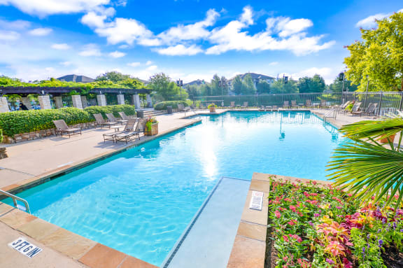 Exterior swimming pool surrounded by greenery at Cypress Lake at Stonebriar Apartments, Frisco, TX, 75034