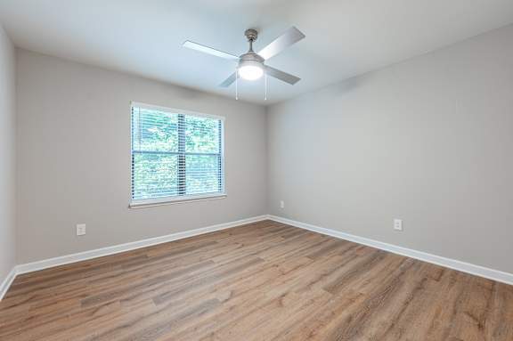 A room with a ceiling fan and a window with blinds.