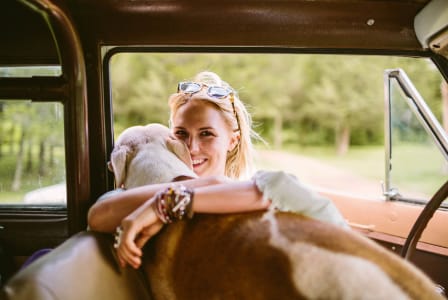 a woman sitting in a car with her dog