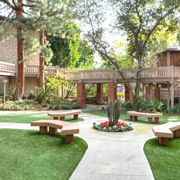 a courtyard with benches in front of a building at The Meadows Apartments, Culver City , CA 90230