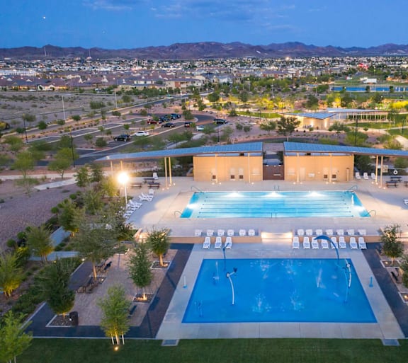 A large swimming pool with a diving board and a building in the background.