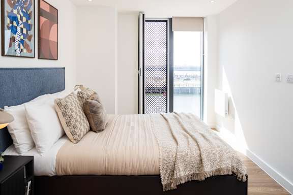 A bedroom with a bed, pillows, and a blanket.