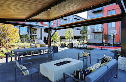 an outdoor lounge area with a firepit and a basketball court