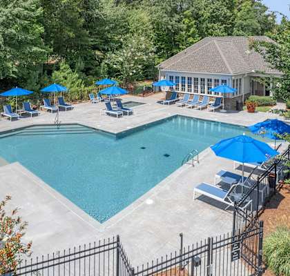 A pool surrounded by trees and a gazebo.