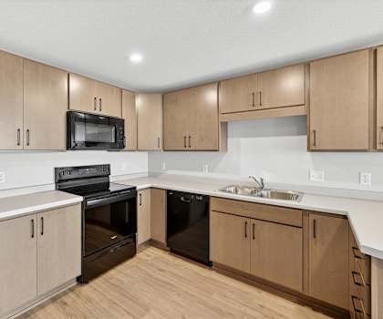 A kitchen with wooden cabinets and black appliances.