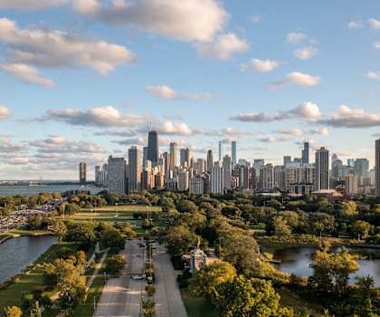 A city skyline is seen from a distance with a river running through the foreground.