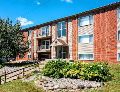 A red brick building with a landscaped front yard.
