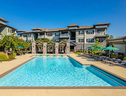 a swimming pool with umbrellas in front of an apartment building