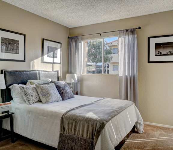 A bedroom with a large bed and a window with curtains.