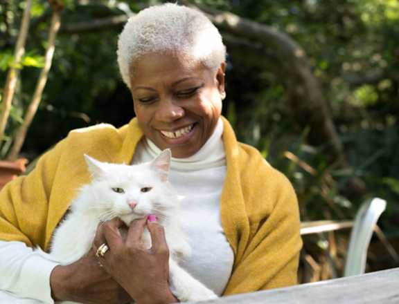 an older woman holding a white cat on her lap
