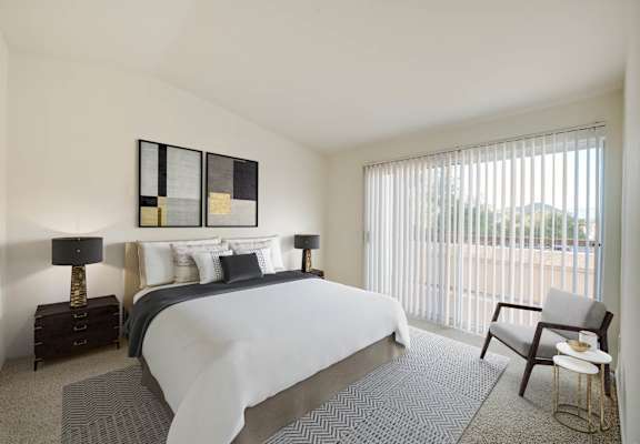 a bedroom with a bed and a chair in a room