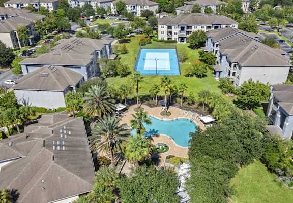 A bird's eye view of a residential area with a swimming pool surrounded by houses.