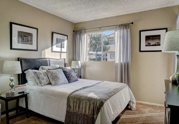 A bedroom with a large bed and a window with curtains.