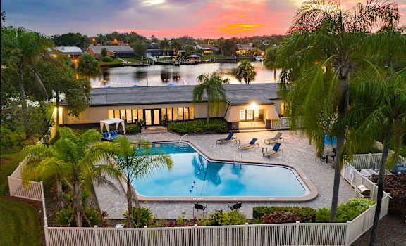 an aerial view of a resort style swimming pool with palm trees and a building in the background