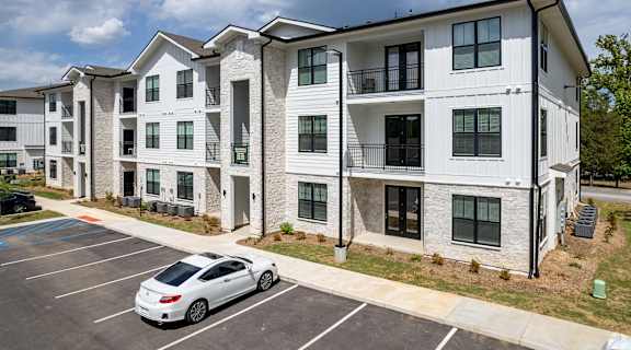 an apartment building with a white car parked in a parking lot
