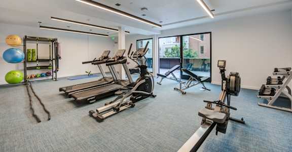 a gym with treadmills and other exercise equipment in a building with windows