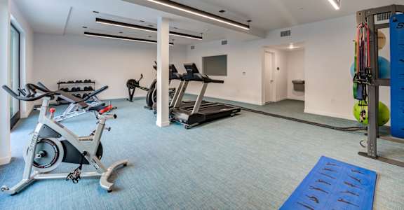 a gym with cardio equipment and weights in a building with white walls