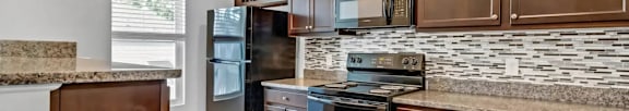A kitchen with dark wood cabinets and a granite countertop.