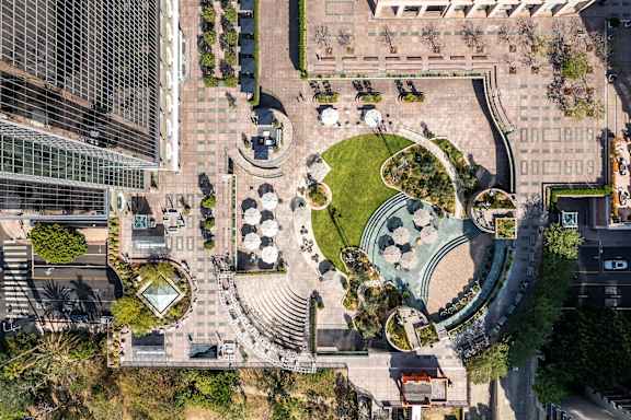 An aerial view of a city square with a large fountain and surrounding buildings.