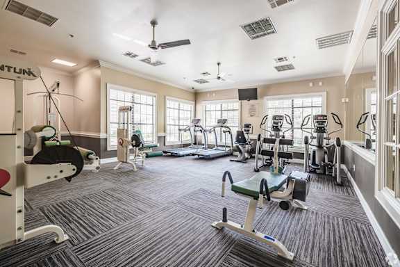 A spacious gym with a variety of equipment including treadmills, exercise bikes, and weight machines.