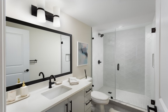 a bathroom with a toilet sink mirror and shower