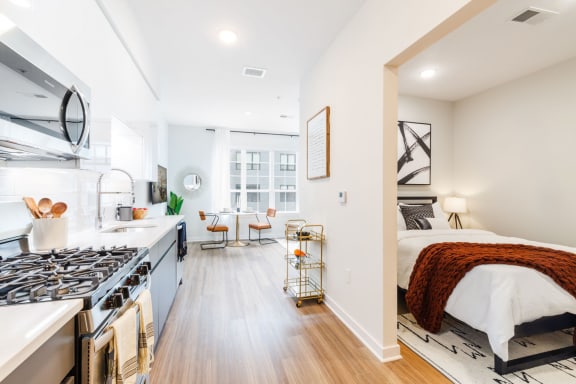 a bedroom with a bed and a kitchen with a stove at One Ten Apartments, New Jersey, 07310