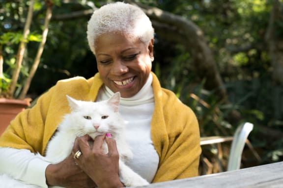 an older woman holding a white cat on her lap