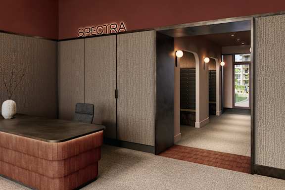 A room with a brown carpet and a brown sofa with a white vase on it.