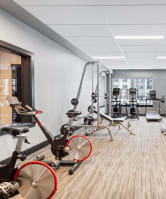 a gym with various exercise equipment and weights on a wooden floor
