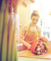 Woman Smiling while Preparing Bouquet of Flowers