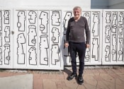 Thumbnail 9 of 9 - a man standing in front of a wall with a drawing of people