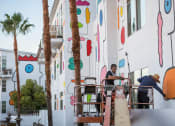 Thumbnail 2 of 9 - two men working on a building with palm trees