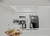 Thumbnail 2 of 8 - A kitchen with a black refrigerator and white cabinets.