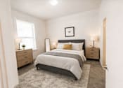 Thumbnail 2 of 8 - A bedroom with a large bed, two nightstands, and a window.
