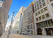 Thumbnail 6 of 7 - A street view of a city with a large building on the right and a truck parked in front of a garage door.