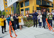 Thumbnail 1 of 16 - A group of people are gathered in front of a building with a sign that reads "Copper.".