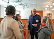 Thumbnail 10 of 16 - A group of people are gathered in a room for a meeting.