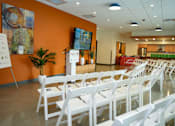 Thumbnail 6 of 16 - A room with white chairs and a white board on a stand.