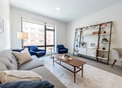Thumbnail 11 of 82 - Apartments for Rent in Beverly, MA- Holmes Beverly- Wood-Style Floors with Floor-to-Ceiling Windows and Comfortable Grey Couch
