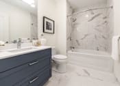 Thumbnail 16 of 82 - Beverly Apartments- Holmes Beverly- Wall Marble in Shower with Marble Floors and Blue Modern Vanity