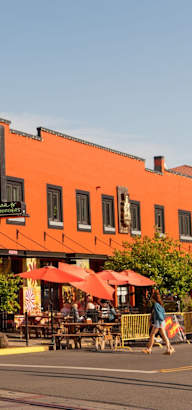 an orange building with tables and umbrellas in front of it on a street